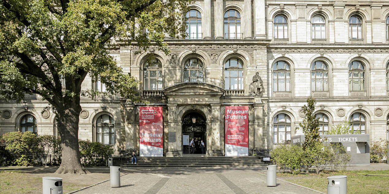 Exterior view of the Museum für Naturkunde Berlin; to the left and right of the entrance the banners, red and white, of the Martin Roth Symposium
